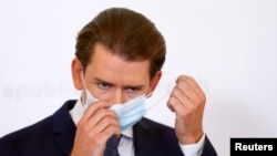 Austrian Chancellor Sebastian Kurz takes off a protective face mask as he arrives for a news conference amid a new coronavirus surge, in Vienna, Austria, Sept. 11, 2020. 