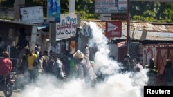 A man throws a tear gas canister back at the police during a protest against Haiti's President Jovenel Moise, in Port-au-Prince, Haiti, Feb. 10, 2021. 