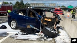 FILE - Photo provided by KTVU shows emergency personnel working at the scene where a Tesla electric SUV crashed into a barrier on U.S. Highway 101 in Mountain View, Calif., March 23, 2018.