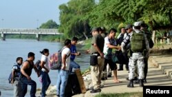 FILE - Members of Mexico's National Guard check people crossing the Suchiate river on a raft from Tecun Uman, Guatemala, to Ciudad Hidalgo, as seen from Ciudad Hidalgo, Mexico, July 3, 2019. 