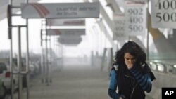 A girl tries to protect herself from the smoke coming from one of the parking lots of Madrid's Barajas airport after a car bomb explosion, which injured four people, December 30, 2006 (file photo)