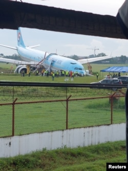 Awak tanggap darurat berkumpul di sekitar pesawat berbadan lebar Korean Air Airbus A330 yang terbang dari Seoul ke Cebu, yang mencoba mendarat dua kali dalam cuaca buruk sebelum menabrak landasan pacu pada upaya ketiga pada hari Minggu, di Kota Lapu-Lapu, Cebu, Filipina 24 Oktober 2022. (Randyl Dungog/via REUTERS)