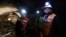 FILE - Foreman Jorge Villanueva, left, and supervisor Omar Rosales, right, look toward the entrance of a tunnel drilled under the Chuquicamata copper mine in the Atacama desert in northern Chile, Sept. 25, 2012.