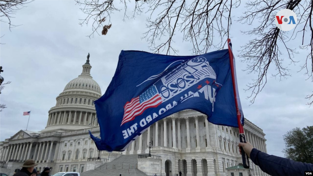 Partidario de Trump alza una bandera que dice &quot;Todos abordo del tren de Trump&quot;.