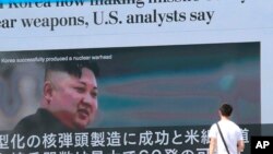 A man walks by a TV news program showing an image of North Korean leader Kim Jong Un while reporting North Korea's rocket launch, in Tokyo, Aug. 9, 2017.