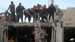 FILE - Palestinians rescue a man from a destroyed building following Israeli airstrikes in Khan Younis refugee camp, southern Gaza Strip, December 7, 2023.