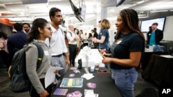 FILE - Georgia State University students Kavita Javalagi, left, and Gana Natarajan, second from left, speak with Shetundra Pinkston, during the Startup Student Connection job fair, March 29, 2023, in Atlanta.