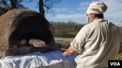 Justin Cherry bakes bread in a clay, wood-fired oven he made. He uses the same kind of wheat that was grown on Mount Vernon during Washington’s time. (Photo: Deborah Block)