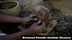 Un potier utilise de la boue pour mouler un visage dans une usine de poterie près des rives du Nil, à Alqamayir, Omdurman, Soudan, le 18 février 2020.