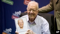 FILE - Former President Jimmy Carter poses for photographs with a copy of his new book "A Full Life: Reflections at Ninety," July 10, 2015, at the Free Library in Philadelphia, Pennsylvania. 