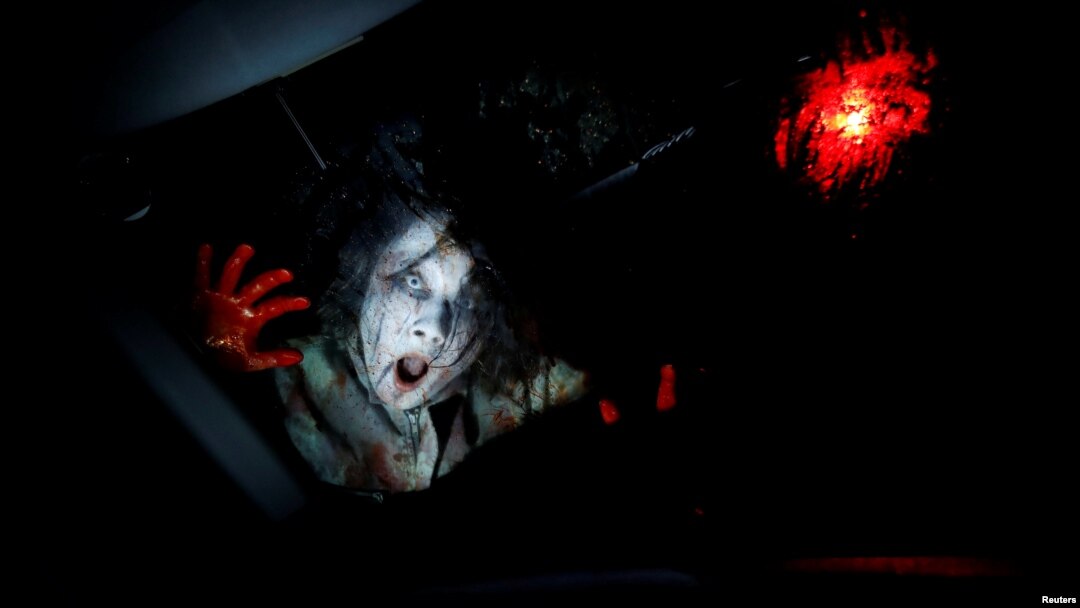 Seorang aktor dari kelompok Kowagarasetai berperan sebagai zombie sedang menakut-nakuti pengunjung dalam mobil di pertunjukan rumah hantu di Tokyo, 3 Juli 2020. (Foto: Reuters)