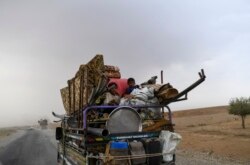 FILE - Displaced Syrians from Deir el Zour head to refugee camps on the outskirts of Raqa, Sept. 24, 2017.