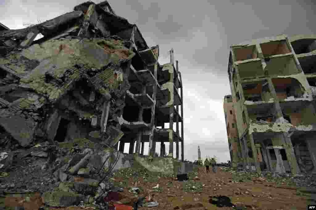 Palestinians walk near the ruins of their house that was destroyed by Israeli shelling during a 50-day war in the summer of 2014, in the northern Gaza Strip town of Beit Lahia.