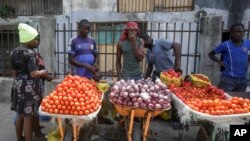 FILE - In this April 13, 2020, file photo, a woman buys tomatoes and onions from street sellers in Lagos, Nigeria. 