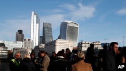 FILE - People gather near London Bridge, backdropped by the city of London financial district, with 20 Fenchurch Street building known as The Walkie-Talkie building, top right, Dec. 11, 2019.