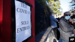 A directional sign at a COVID-19 testing site is seen near a growing line of test seekers in the northern Italian town of Bozen on Friday, November 20, 2020. (AP Photo/Antonio Calanni)