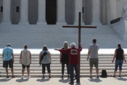 Demonstrators gather outside the U.S. Supreme Court as the court ruled that religious institutions like churches and schools are shielded from employment discrimination lawsuits in Washington, July 8, 2020.