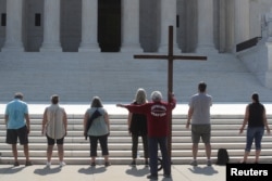 Demonstrators gather outside the U.S. Supreme Court as the court ruled that religious institutions like churches and schools are shielded from employment discrimination lawsuits in Washington, July 8, 2020.