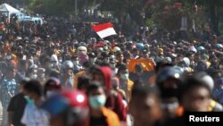 Seorang peserta unjuk rasa mengibarkan bendera saat berpawai ke gedung DPRD Sulawesi Tenggara di Kendari, Sulawesi Tenggara, 26 September 2019. (Foto: Antara via Reuters)