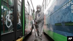 A worker wearing a protective suit sprays disinfectant as a precaution against the coronavirus at a bus garage in Seoul, South Korea, Feb. 26, 2020. 