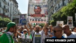 FILE: In this photo from Sept. 27, 2019, an Algerian protester marches with a sign calling to free politician Karim Tabbou, during a demonstration against the ruling class in the capital Algiers for the 32nd consecutive Friday since the movement began.