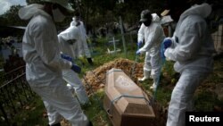 7일 브라질 파라주 브레베스에서 장례식 업체 직원이 신종 코로나바이러스 감염증(COVID-19) 사망자 시신을 묻고 있다. 
