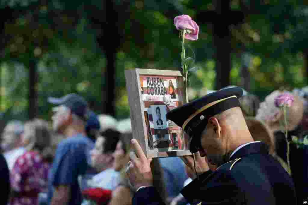 A man holds a photo of a victim during a ceremony marking the 18th anniversary of the attacks of Sept. 11, 2001 at the National September 11 Memorial, Sept. 11, 2019, in New York.