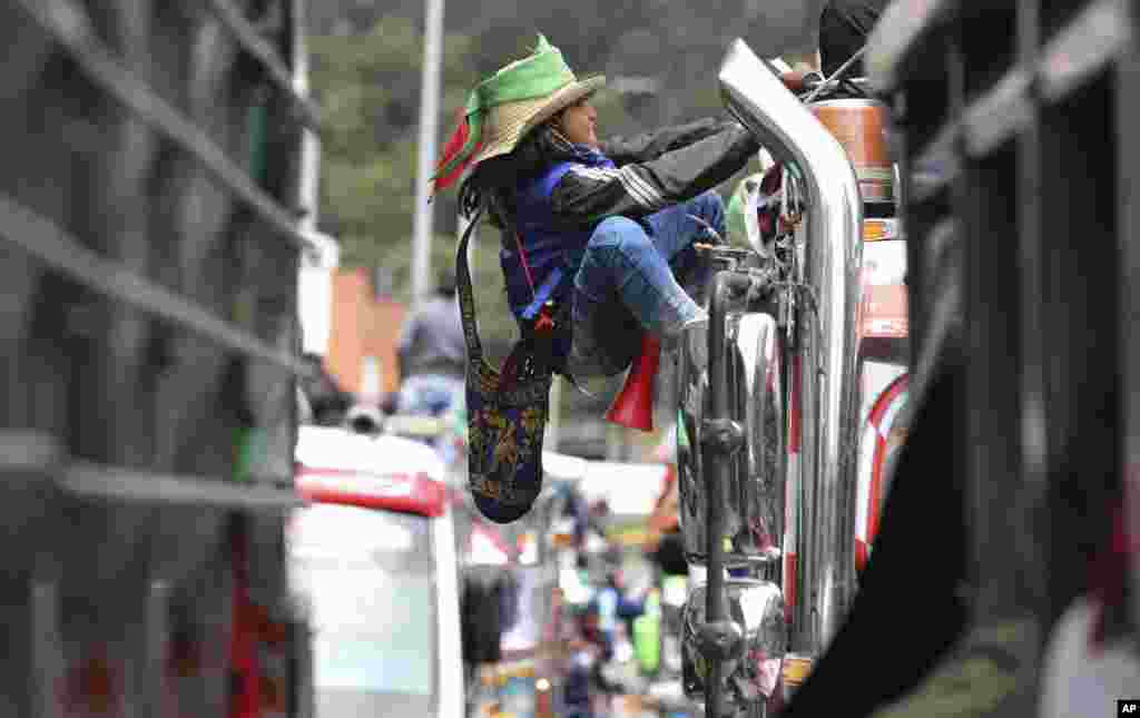 An Indigenous youth climbs the side of a bus during a national strike in Bogota, Colombia, Wednesday, Oct. 21, 2020. Workers&#39; unions, university students, human rights defenders, and Indigenous communities held a day of protest in conjunction with a natio