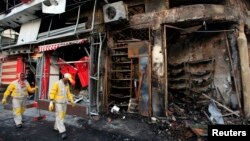 Municipal workers clean the site of a bomb attack in Baghdad's Karrada district, Feb. 18, 2014. 