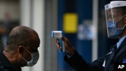 Le toman la temperatura a un hombre en la entrada del centro comercial El Recreo en Caracas, el 17 de junio de 2020, como medida para evitar la propagación del coronavirus..