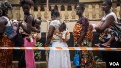 Des mères avec leurs bébés font la queue pour voter dans un bureau à Freetown, en Sierra Leone, le 7 mars 2018. (VOA/Jason Patinkin) 