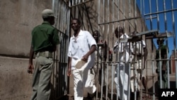 FILE: Prison Inmates walk past a prison guard at the Chikurubi Maximum security prison in Harare, Zimbabwe, May 20, 2015 during a tour by a parliamentary committee to assess the state of the nation's prisons.