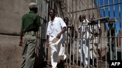 Des détenus de la prison passent devant un gardien de prison à la prison de sécurité maximale de Chikurubi à Harare, Zimbabwe le 20 mai 2015 