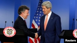 U.S. Secretary of State John Kerry (R) and Colombia's President Juan Manuel Santos shake hands as they address a joint news conference after their meeting at the presidential palace in Bogota, Dec. 12, 2014.