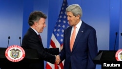 U.S. Secretary of State John Kerry (R) and Colombia's President Juan Manuel Santos shake hands as they address a joint news conference after their meeting at the presidential palace in Bogota, Dec. 12, 2014.