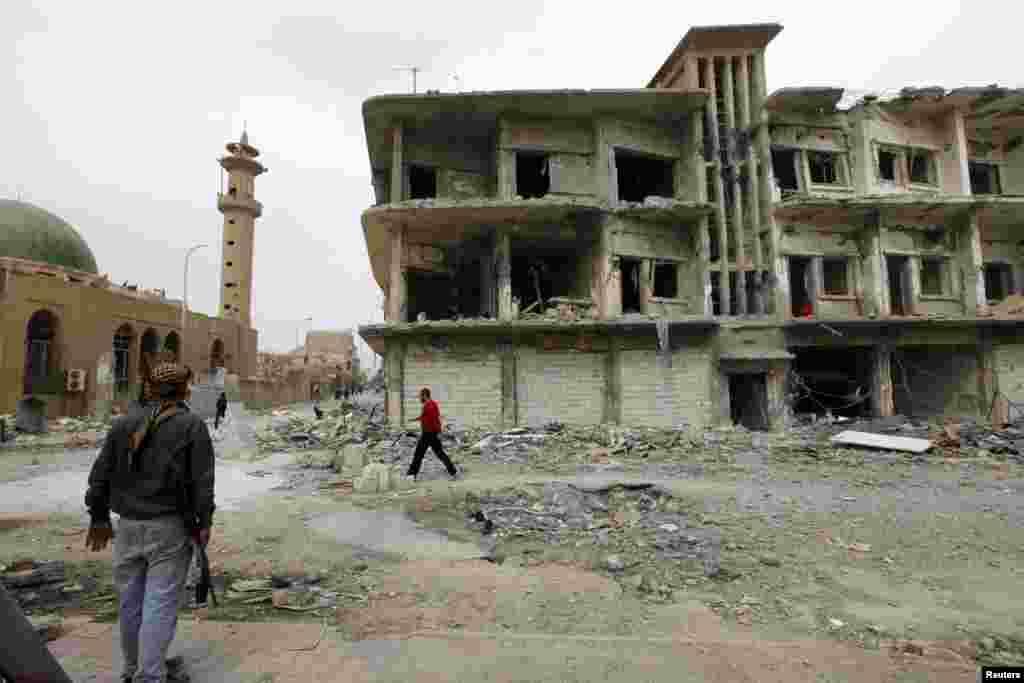 A member of the Free Syrian Army stands near a damaged building in Raqqa province, eastern Syria, March 13, 2013. 