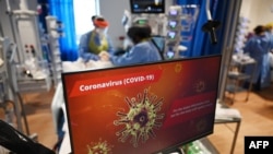 Le personnel clinique porte un équipement de protection individuelle (EPI) pendant qu'il s'occupe d'un patient à l'unité de soins intensifs du Royal Papworth Hospital de Cambridge, le 5 mai 2020. (Photo de Neil HALL / POOL / AFP)