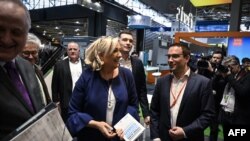 President of the far-right National Rally party and French MP Marine Le Pen (C) and French far-right 'RN' runner candidate for the upcoming European election Jordan Bardella (C-R) visit the annual energy transition fair "BePOSITIVE" exhibit, Feb. 14, 2019, Chassieu, France.