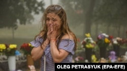 A woman cries near flowers brought to the destroyed Amstor shopping mall in Kremenchuk on June 28, 2022. (Oleg Petrasyuk/EPA-EFE)