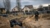 A Ukrainian soldier reacts after paying his respects next to a mass grave in Bucha. April 6, 2022. (Alkis Konstantinidis/Reuters)