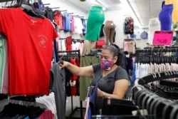 A woman shops for women's shirts in a Mini-Max store, June 8, 2020, in the Sunset Park neighborhood of Brooklyn, in New York, as retail stores were allowed to open, but with some restrictions.