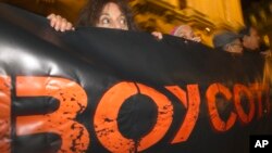 FILE - In this Oct. 31, 2012, French demonstrators and supporters of Palestinians hold a placard with the word "Boycott" during a demonstration in Paris.