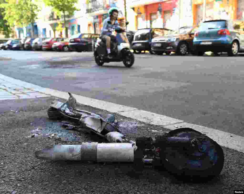 A burned electric scooter is seen at a roadside in the Friedrichshain area of Berlin, Germany.