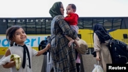 FILE - Afghan refugees board buses that will take them to a processing center after arriving at Dulles International Airport in Dulles, Va., Sept. 2, 2021.