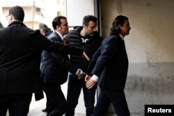 FILE - Two of the eight Turkish soldiers, who fled to Greece in a helicopter and requested political asylum after a failed military coup against the government, are escorted by police officers as they arrive at the appeals court in Athens, Greece, March 1