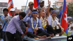 Anti-government protesters who had been in prison since their arrest in January, wave from atop a truck during a rally, in Phnom Penh, Cambodia, Friday, May 30, 2014. A Cambodian court on Friday convicted almost two dozen factory workers and rights activists for instigating violence during protests that rocked the government earlier this year, but in a surprise move gave them suspended sentences and granted them freedom. (AP Photo/Heng Sinith)