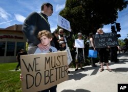 Kyle Fox, 4, and his father Brady Fox hold a sign at a vigil held to support the victims of Chabad of Poway synagogue shooting, April 28, 2019, in Poway, Calif.