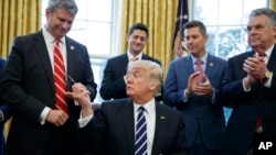 FILE - President Donald Trump hands a pen to Congressman Bill Huizenga, R-Michigan, after signing House Joint Resolution 41 in the White House in Washington, Feb. 14, 2017.