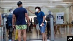 Un empleado usando una máscara protectora monitorea el flujo de clientes en una tienda de Apple en Miami Beach, Florida, el 17 de junio de 2020.