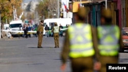 Police officers stand guard at an area where a bomb exploded in Santiago, Chile, Sept. 25, 2014.